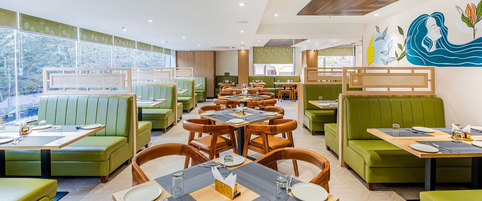 Lemonridge Hotels, KPHB | Dining area with set tables, green booth seating, and artistic wall decorations. Modern design.